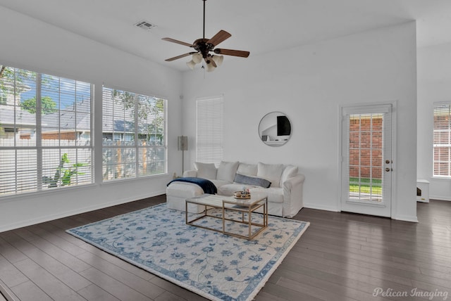 living room with dark wood-type flooring, a wealth of natural light, and ceiling fan