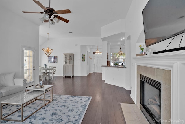 living room with ceiling fan, dark hardwood / wood-style flooring, high vaulted ceiling, and a tile fireplace