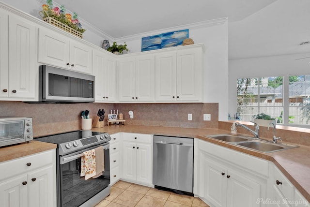 kitchen featuring white cabinets, light tile patterned flooring, ornamental molding, sink, and stainless steel appliances