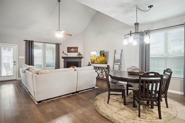 dining area with ceiling fan with notable chandelier, dark wood-type flooring, and high vaulted ceiling