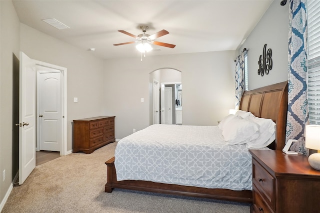 bedroom featuring light colored carpet, ensuite bathroom, and ceiling fan