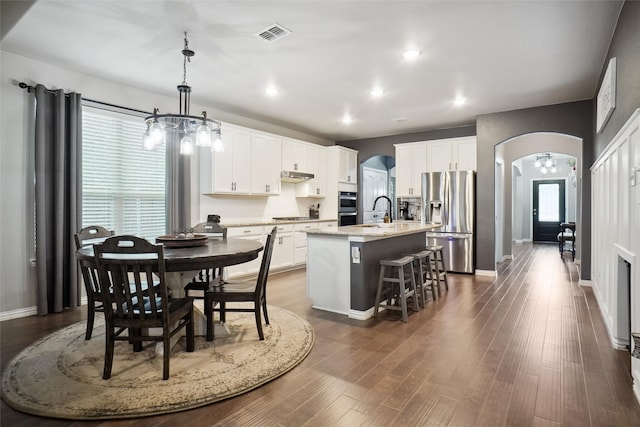 kitchen with appliances with stainless steel finishes, a healthy amount of sunlight, a kitchen island with sink, and white cabinets