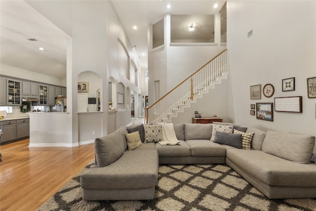 living room featuring a towering ceiling and light wood-type flooring