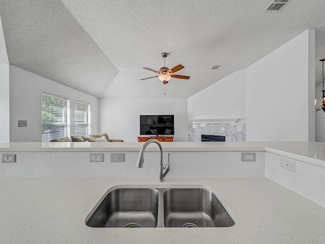 kitchen with light stone countertops, a textured ceiling, ceiling fan, and sink