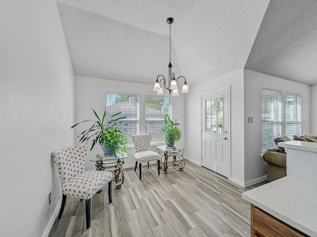 interior space featuring a textured ceiling, lofted ceiling, light hardwood / wood-style flooring, and a chandelier