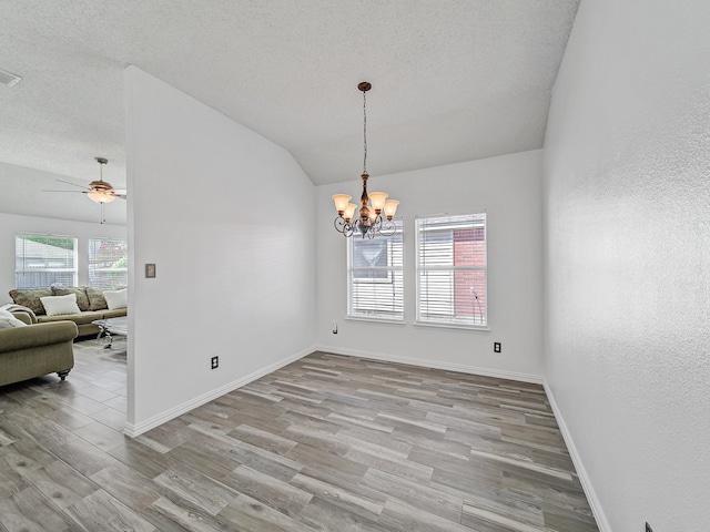 spare room featuring ceiling fan with notable chandelier, light hardwood / wood-style floors, and a wealth of natural light