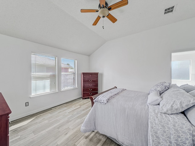 bedroom with light hardwood / wood-style flooring, lofted ceiling, ceiling fan, and a textured ceiling