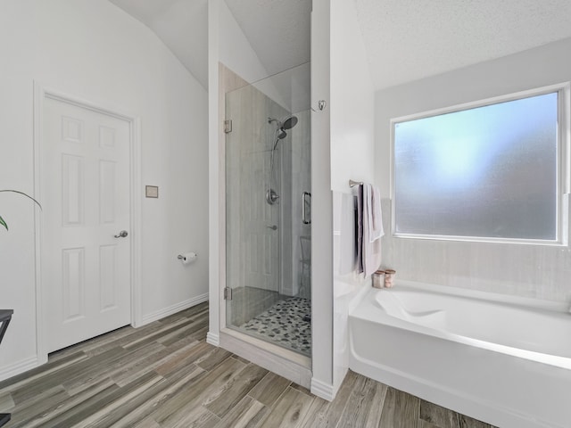 bathroom with a textured ceiling, wood-type flooring, lofted ceiling, and plus walk in shower