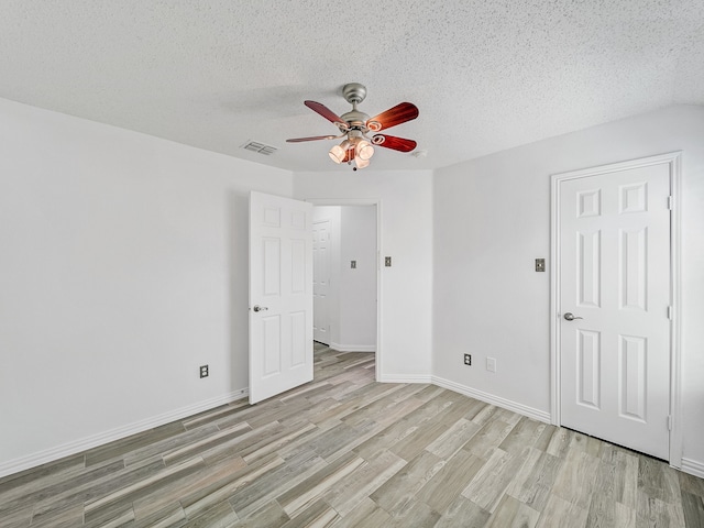 spare room with light hardwood / wood-style floors, ceiling fan, and a textured ceiling