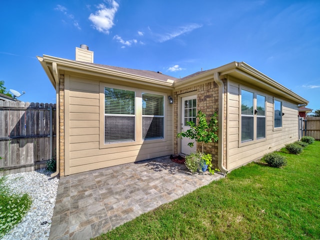 rear view of house featuring a lawn and a patio area