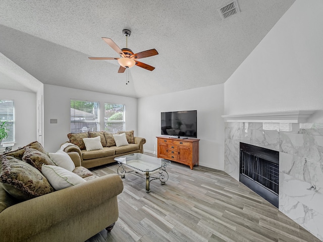 living room with light hardwood / wood-style flooring, a wealth of natural light, ceiling fan, and a fireplace