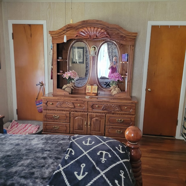 bedroom featuring dark wood-type flooring and wood walls