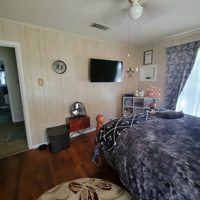 bedroom featuring ceiling fan, dark wood-type flooring, and wood walls