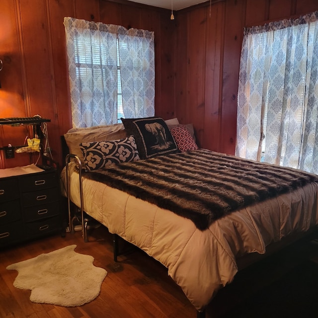 bedroom with wood-type flooring and wooden walls