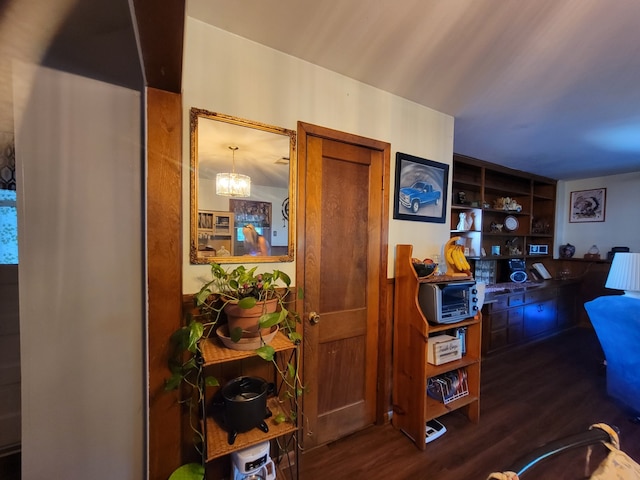 hallway featuring built in shelves, a notable chandelier, and hardwood / wood-style flooring