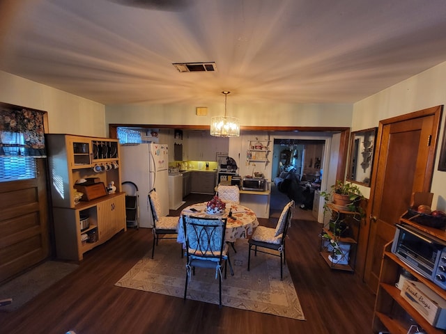 dining area with dark hardwood / wood-style floors and a notable chandelier