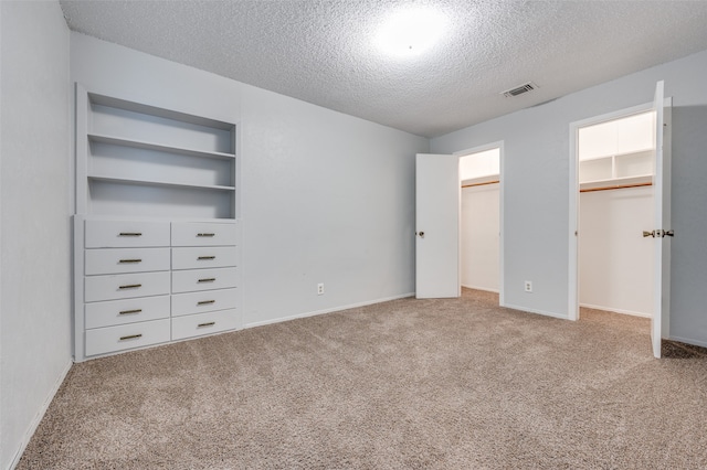 unfurnished bedroom with a textured ceiling and light colored carpet