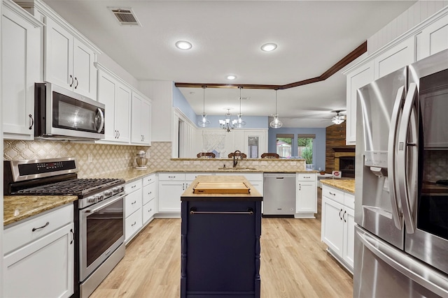 kitchen with a kitchen island, appliances with stainless steel finishes, pendant lighting, white cabinets, and kitchen peninsula