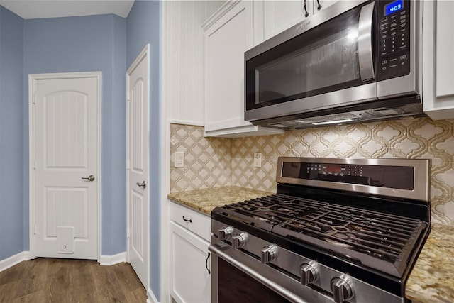 kitchen featuring stainless steel appliances, dark hardwood / wood-style flooring, white cabinets, decorative backsplash, and light stone countertops