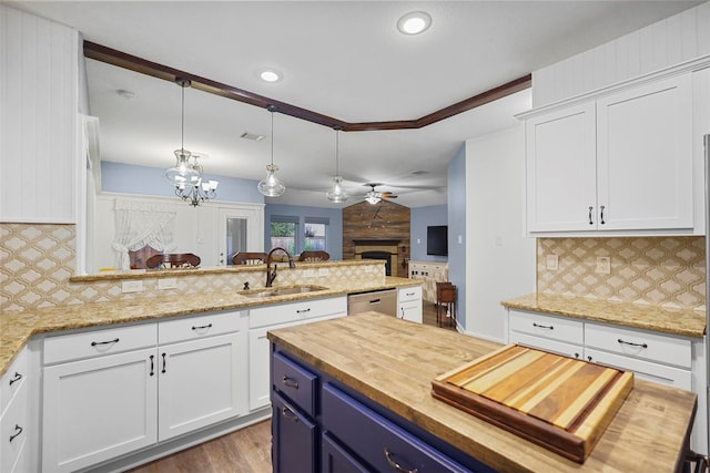 kitchen with white cabinetry, pendant lighting, wooden walls, and sink