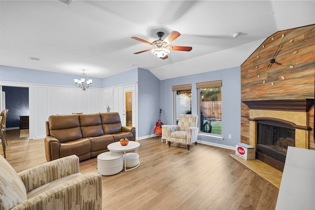 living room with light wood-type flooring, a large fireplace, vaulted ceiling, and ceiling fan with notable chandelier