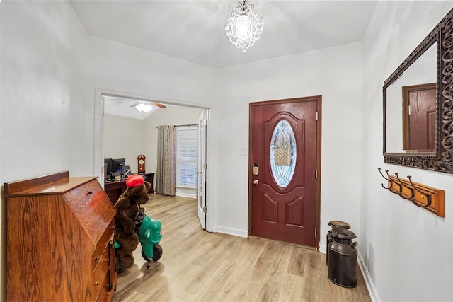 entryway featuring ceiling fan with notable chandelier and light wood-type flooring