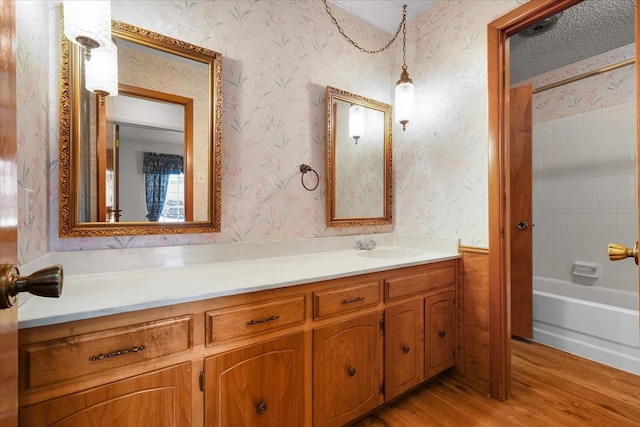 bathroom featuring shower / bathtub combination, vanity, wood-type flooring, and a textured ceiling