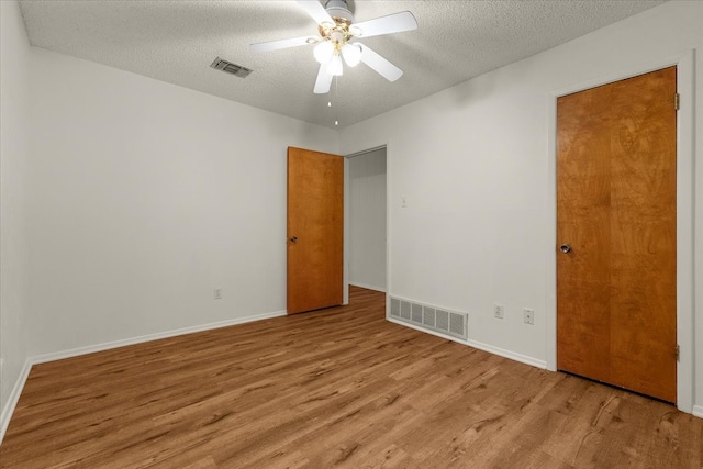 empty room with ceiling fan, light hardwood / wood-style floors, and a textured ceiling