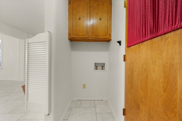 clothes washing area featuring light tile patterned flooring, washer hookup, and cabinets