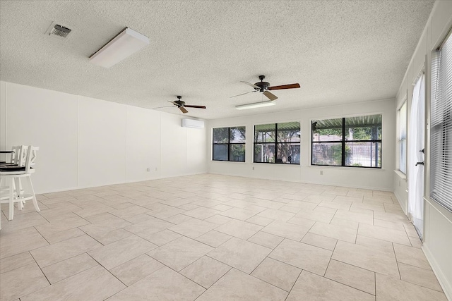 tiled spare room featuring ceiling fan, a wall mounted AC, and a textured ceiling