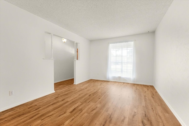 spare room with a textured ceiling and light hardwood / wood-style flooring