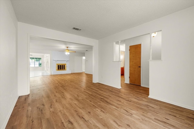 unfurnished living room featuring a textured ceiling, a fireplace, and light hardwood / wood-style floors