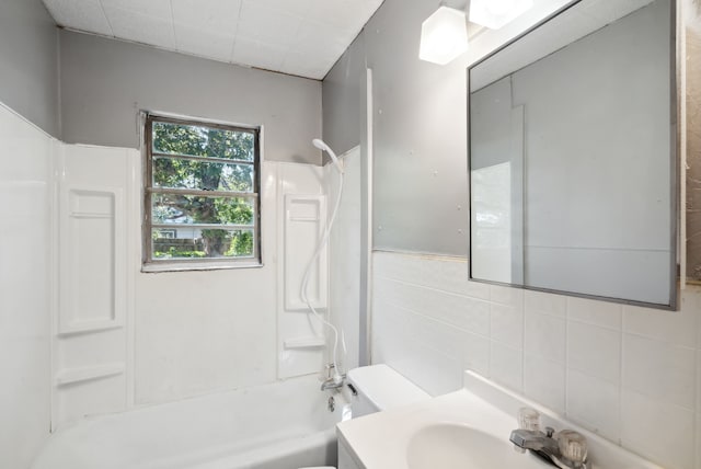 full bathroom with washtub / shower combination, tile walls, toilet, and vanity