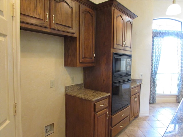 kitchen with black appliances, light stone counters, and light tile patterned floors