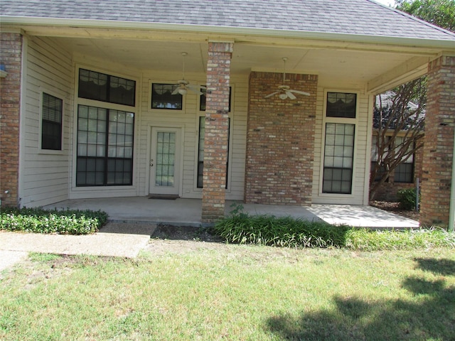 doorway to property with ceiling fan, a patio area, and a lawn