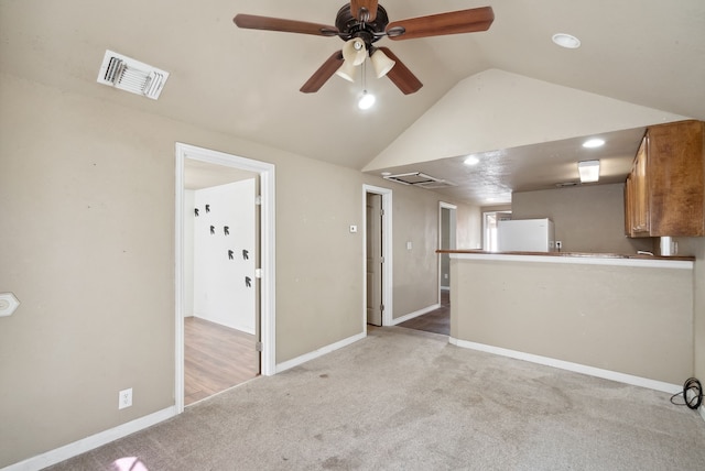 unfurnished living room with vaulted ceiling, light carpet, and ceiling fan