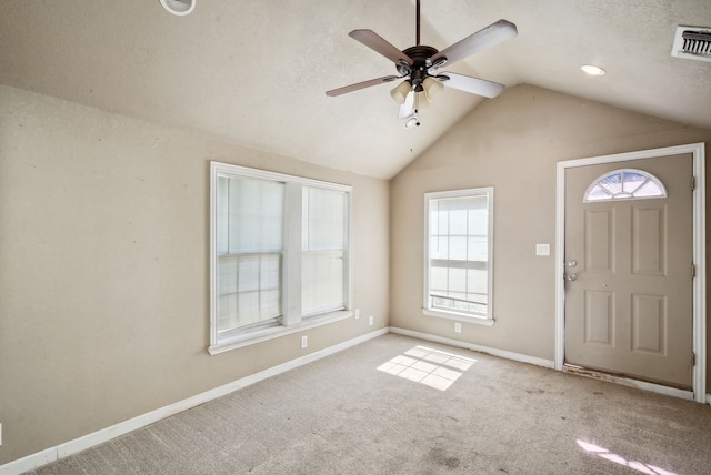 carpeted foyer entrance with ceiling fan, a textured ceiling, and vaulted ceiling