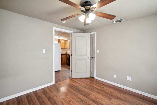 unfurnished bedroom featuring ceiling fan, hardwood / wood-style flooring, and white fridge