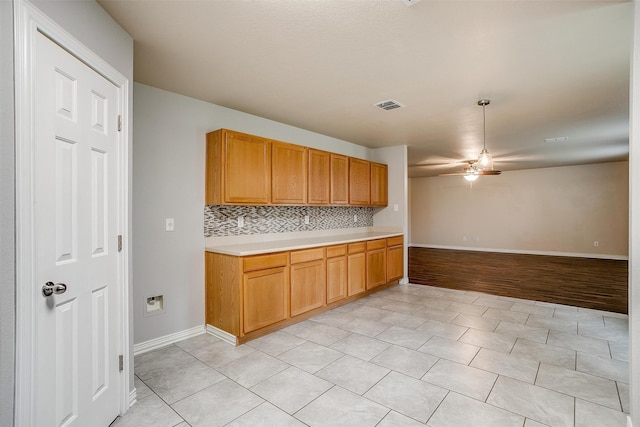 kitchen with light wood-type flooring, ceiling fan, and tasteful backsplash