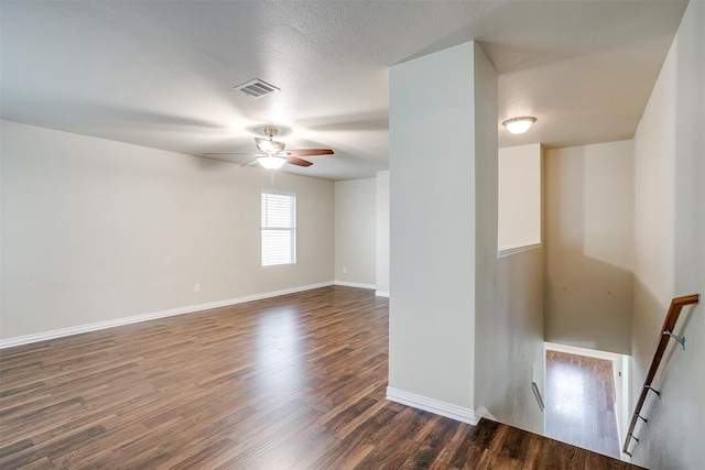 unfurnished room with ceiling fan, a textured ceiling, and dark wood-type flooring