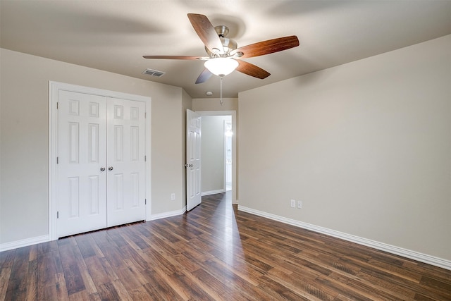 unfurnished bedroom featuring dark hardwood / wood-style flooring, ceiling fan, and a closet