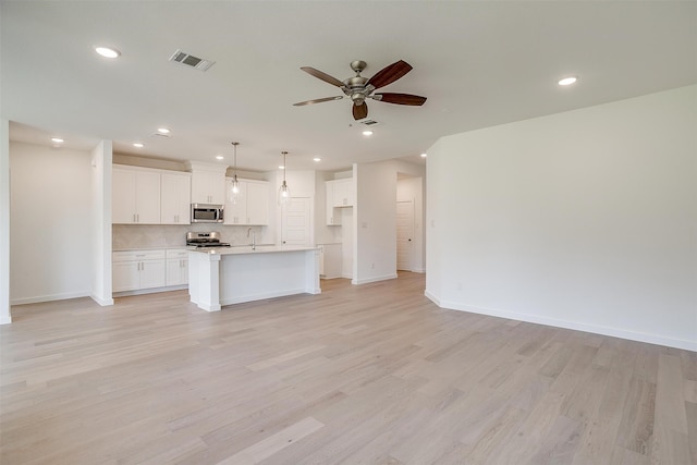 kitchen featuring white cabinetry, stainless steel appliances, light hardwood / wood-style flooring, and an island with sink