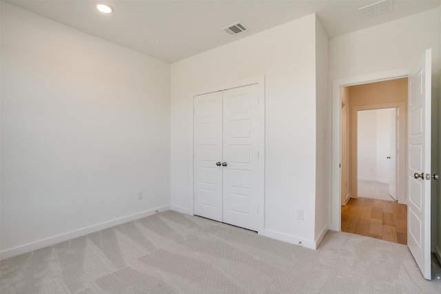 unfurnished bedroom featuring a closet and light colored carpet