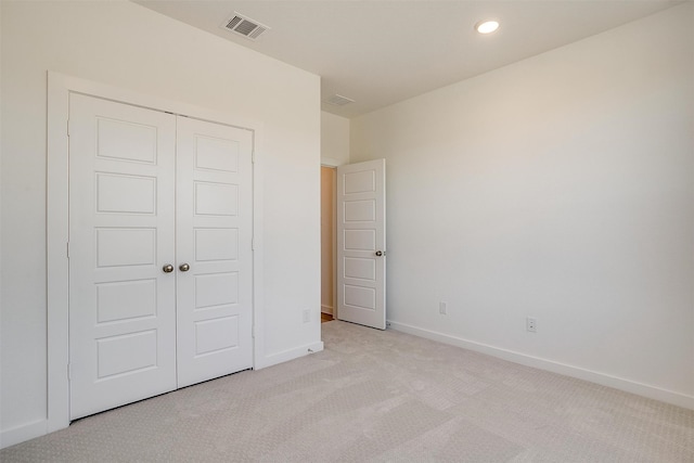 unfurnished bedroom featuring light carpet and a closet