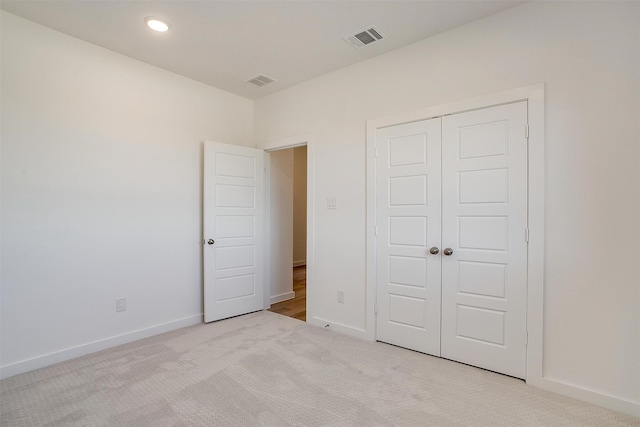 unfurnished bedroom featuring light colored carpet and a closet