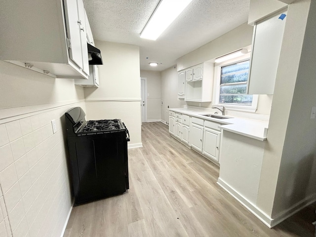 kitchen with light wood-type flooring, a textured ceiling, sink, white cabinets, and black range oven