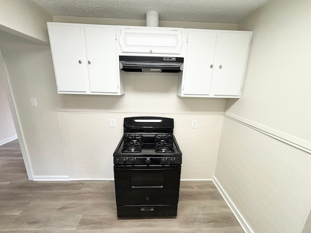 kitchen with a textured ceiling, black gas stove, light wood-type flooring, and white cabinetry