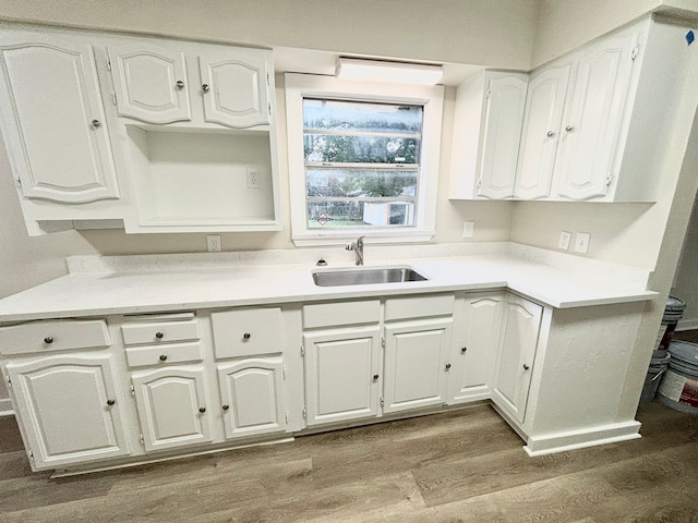 kitchen with light wood-type flooring, white cabinetry, and sink