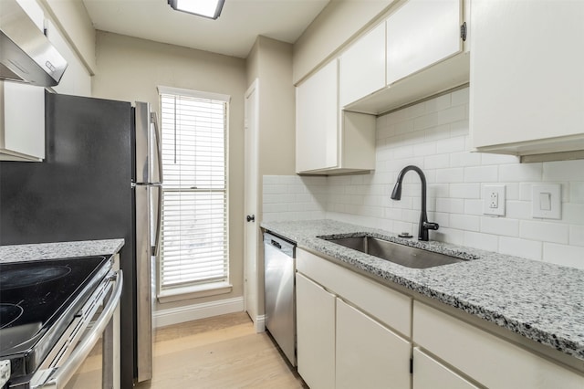 kitchen with wall chimney exhaust hood, stainless steel appliances, sink, light wood-type flooring, and white cabinetry