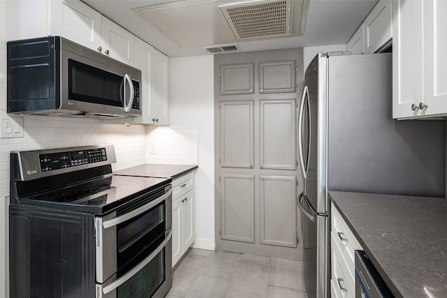 kitchen with white cabinets, stainless steel appliances, backsplash, and light tile patterned floors